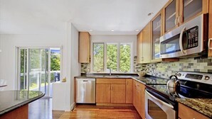 Een moderne keuken met houten kasten, een roestvrijstalen magnetron en een vaatwasser.