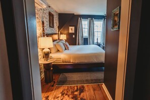 A bedroom with a bed, bedside lamps, a rug, a window with curtains, and a wall with a picture. - Hideaway Inn Lenox (Lenox)