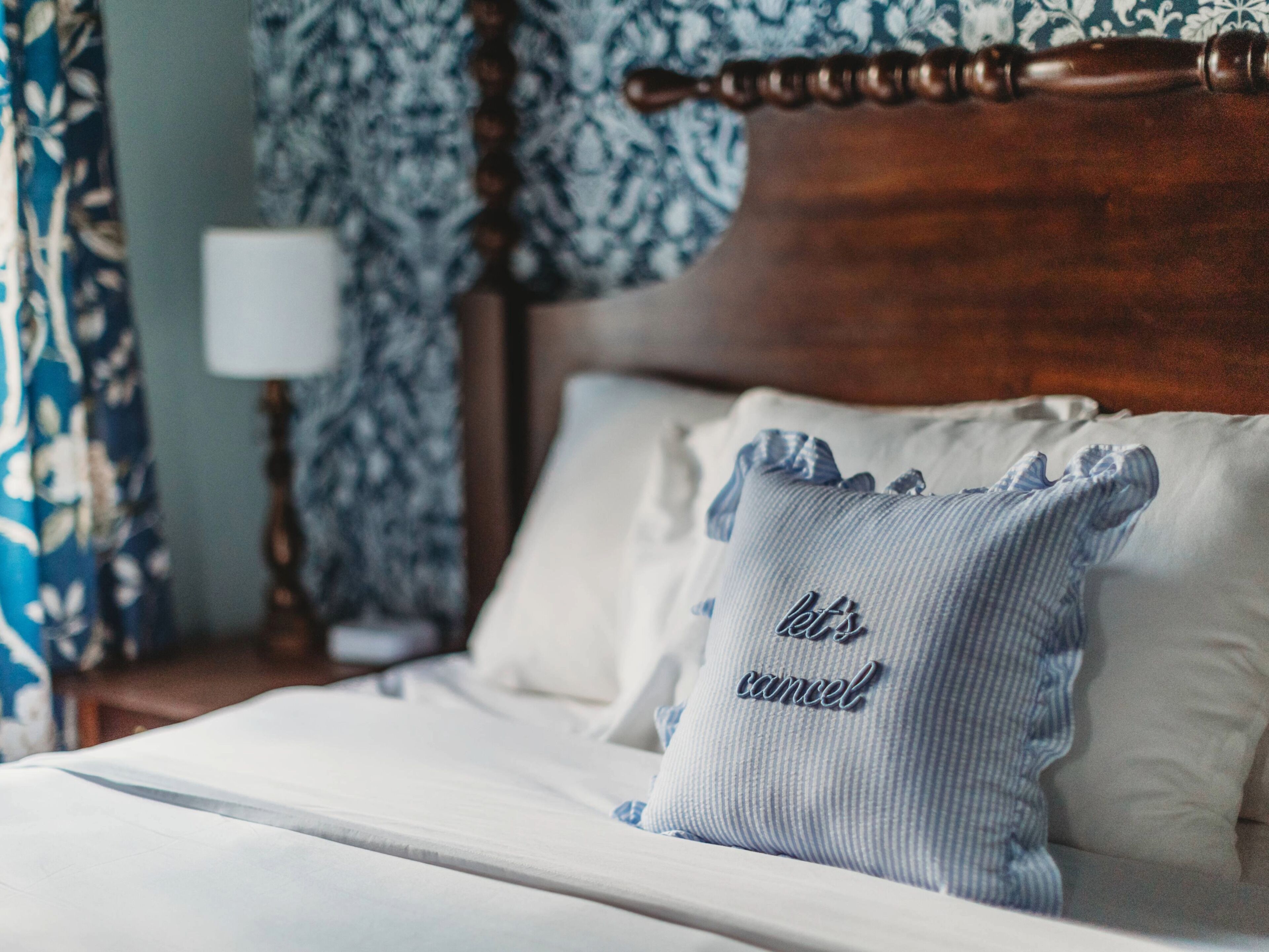 A neatly made bed with a pillow that reads 'let's cancel.'