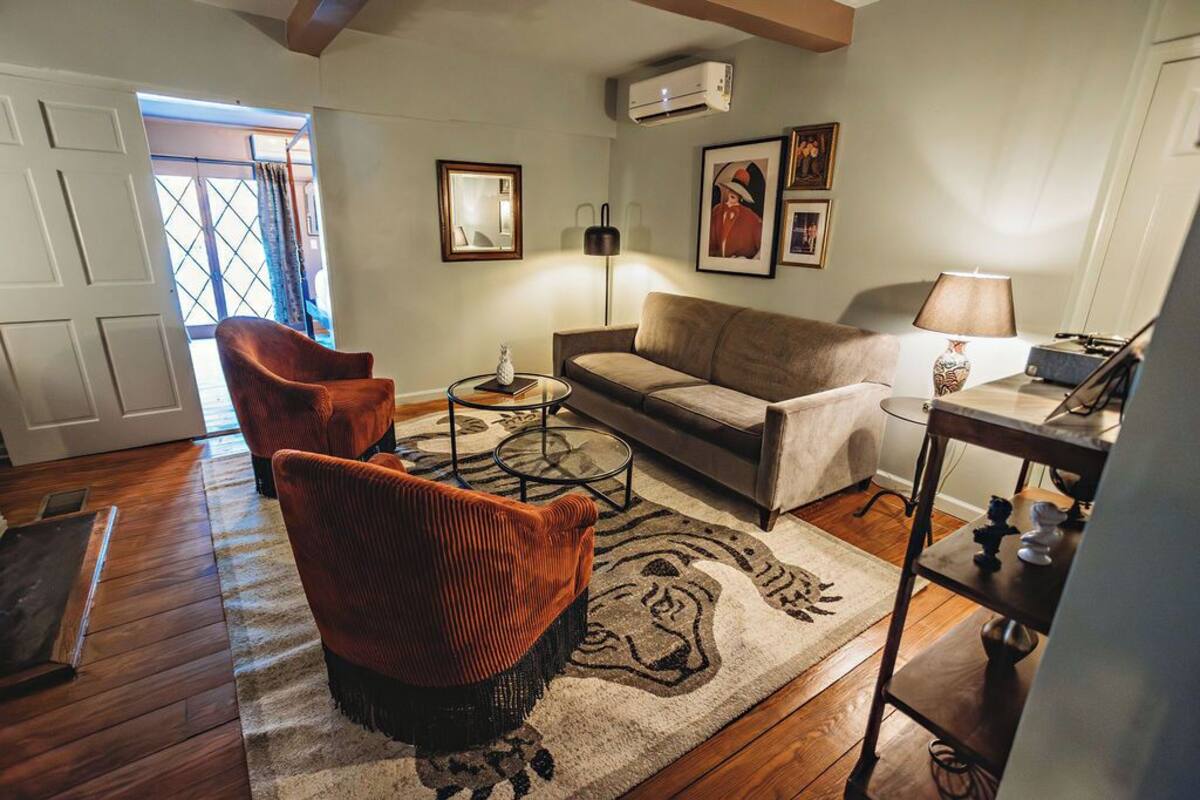 A living room with a sofa, two armchairs, a coffee table, and a rug.