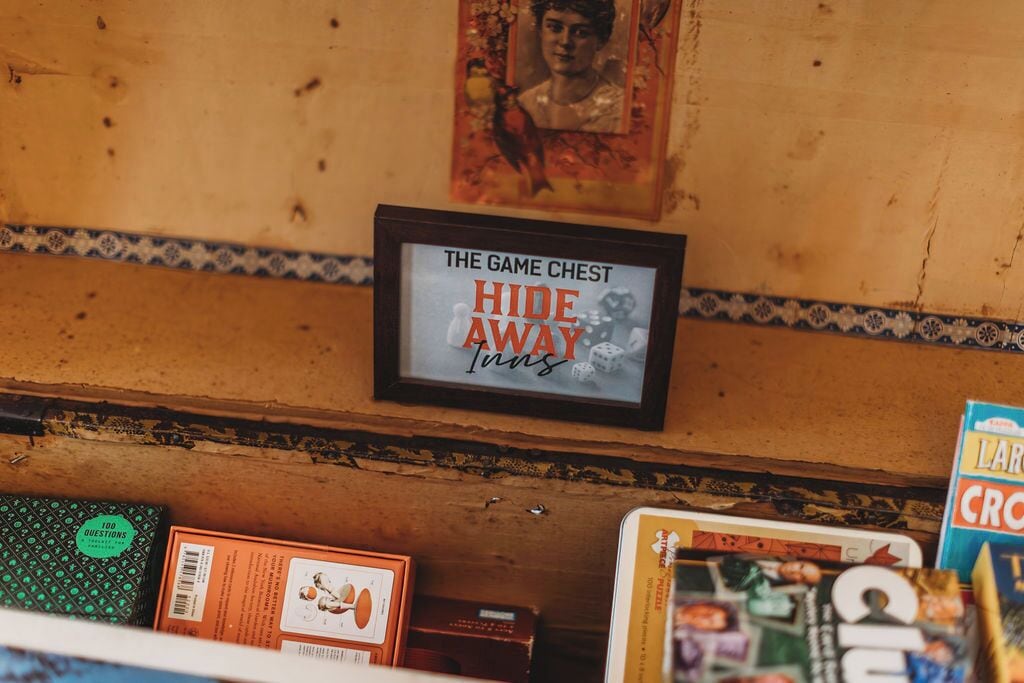 Un mur en bois sur lequel est fixée une enseigne encadrée portant l’inscription : « The Game Chest Hide Away Inns ».