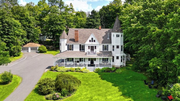 A large white house with a prominent tower, surrounded by lush greenery and a well-maintained lawn. - Hideaway Inn Lenox (Lenox)