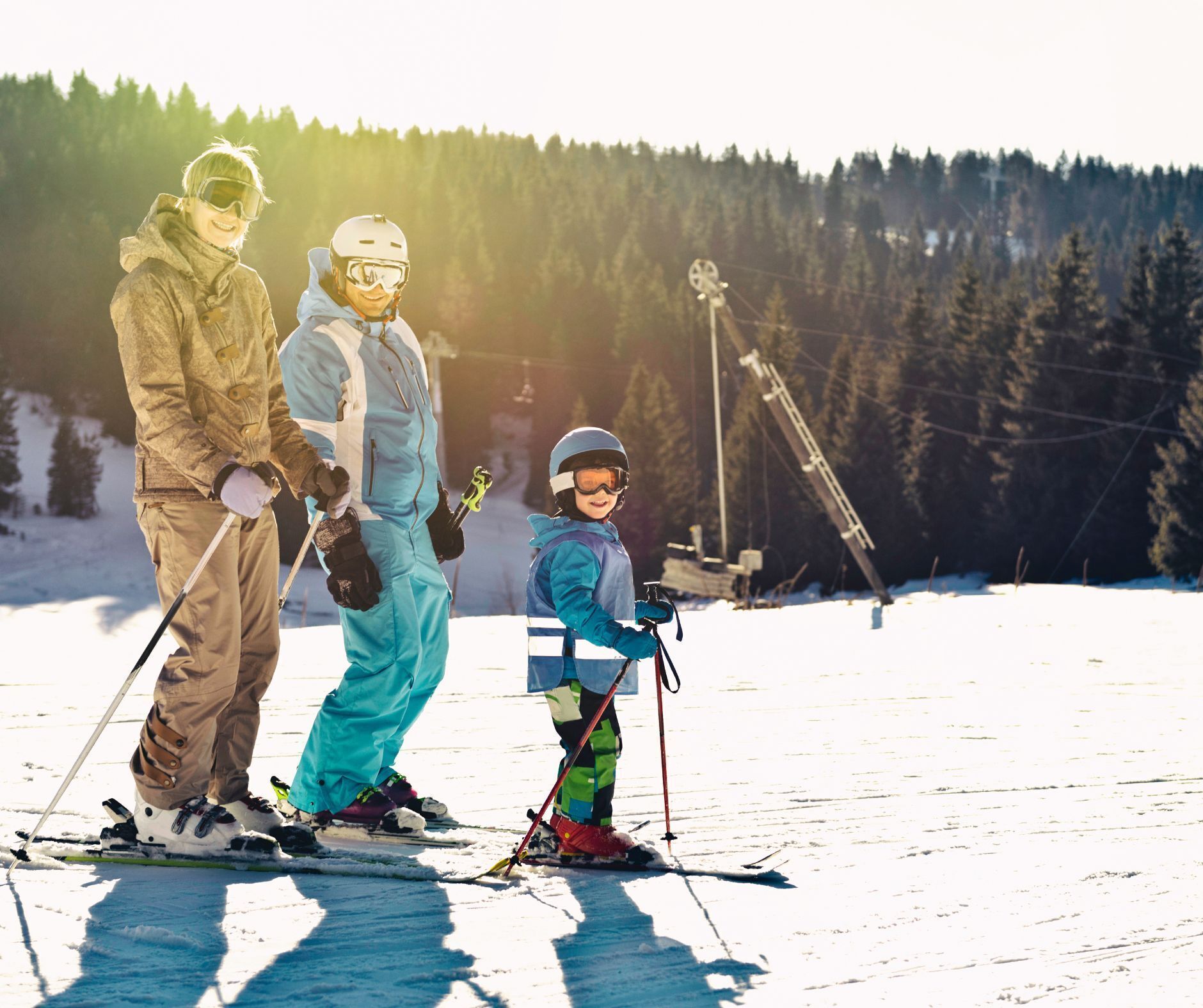 A family on skis at a ski resort with a forested backdrop.