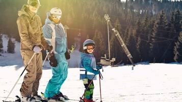 A family on skis at a ski resort with a forested backdrop.