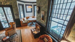 A cozy room with a round table, a sofa, a leopard-print armchair, and a large window with a view. - Hideaway Inn Lenox (Lenox)