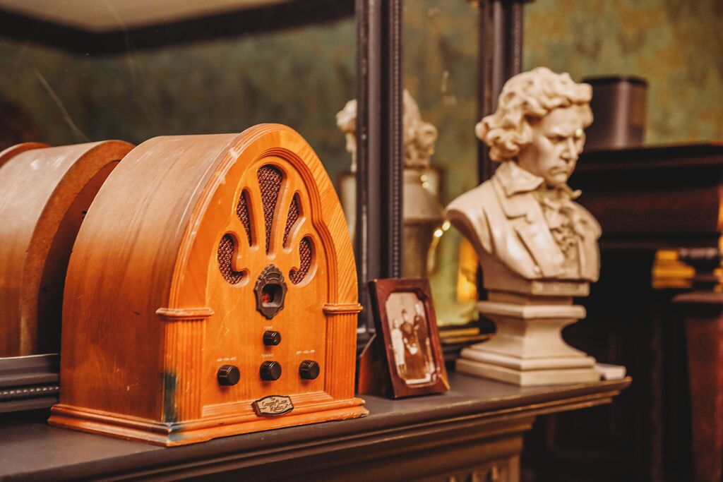 A vintage radio, a bust sculpture, and a framed photograph on a shelf.