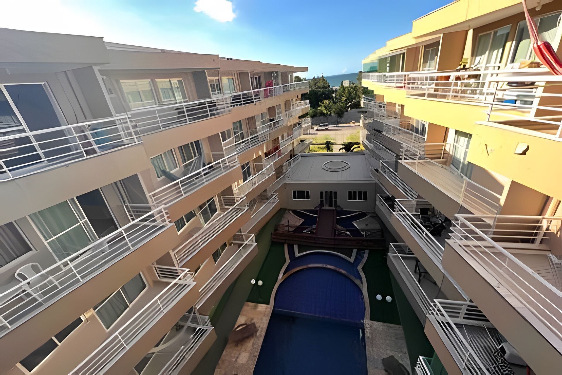 Un hotel de varios pisos con balcones, un patio central y una piscina.