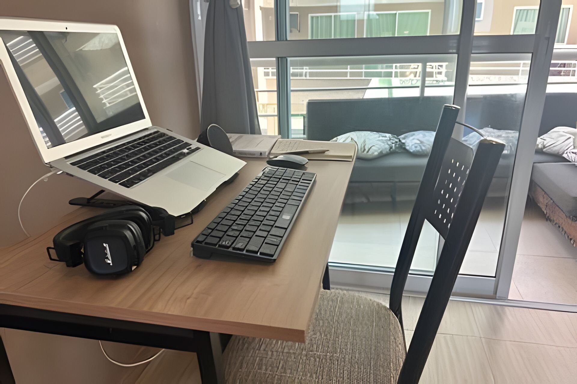 Una computadora portátil sobre un escritorio de madera, un teclado, auriculares y un ratón.
