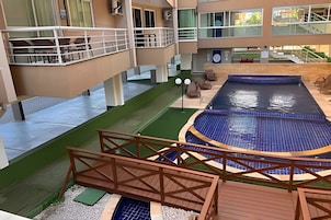 Una piscina interior con un puente de madera, rodeada por un edificio con balcones y una zona verde.
