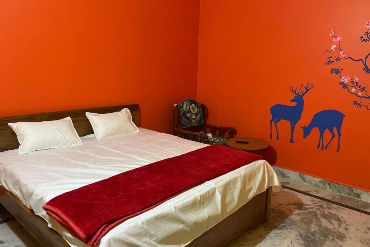 A bed with white and red bedding, a wooden headboard, and a red throw blanket.