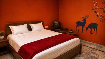 Una habitación con una cama, una mesita de noche, una pequeña mesa y un mural de un ciervo en la pared.