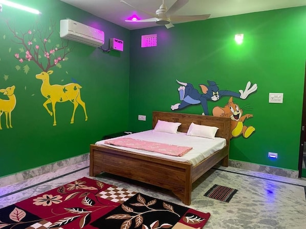 A bedroom with a green wall, a bed with white bedding, and cartoon characters. - ARYA RESIDENCY (Khandaparha)