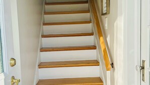 A staircase with wooden steps and a handrail, leading to a door with a brass doorknob. - 2 Bedroom Apartment Suite  in Quiet Neighborhood (Hempstead)