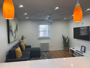 Ein modernes Wohnzimmer mit einer Couch, einem Couchtisch, einem Fernseher und einem Deckenventilator.