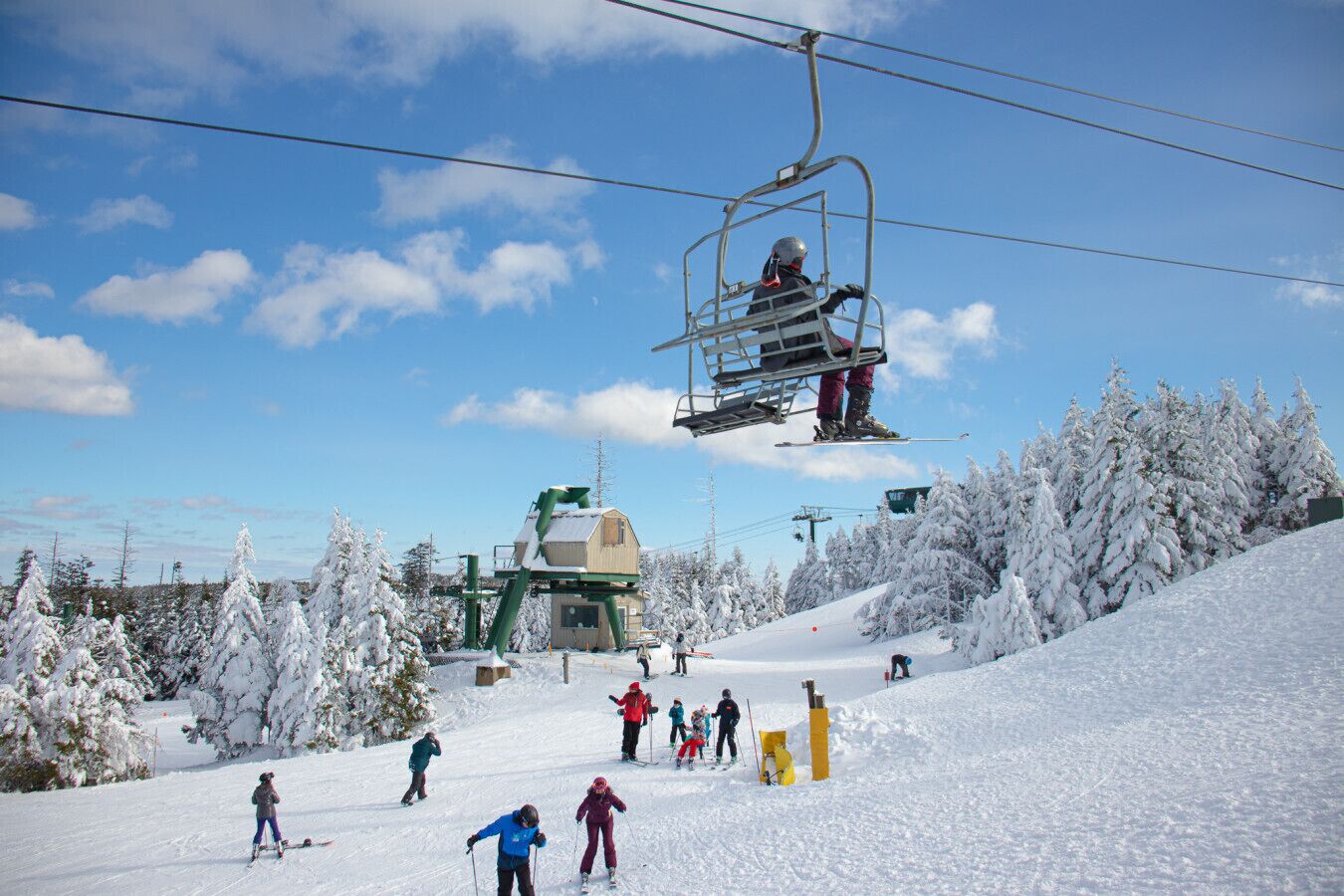 A ski lift with skiers and a snow-covered landscape.