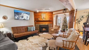 A cozy living room with a fireplace, a television, and a Christmas tree. - Summit 104D Beautiful 3BR, 2BA condo in The Summit at Snowshoe (Snowshoe)