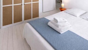 Un dormitorio con cama, armario y mesita de noche con lámpara.