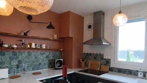 Una cocina moderna con una encimera curva, una botella de vino y una cesta de fruta.