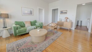 Ein Wohnzimmer mit einem grünen Sofa, einem runden Couchtisch, einer Holzkabine und einem gemusterten Teppich.