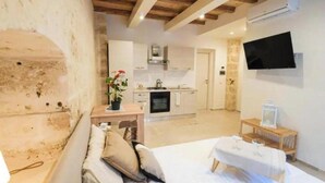 A cozy room with a bed, a small table with a glass, and a TV mounted on the wall. - Urban Flat Garibaldi 36 (Bari)
