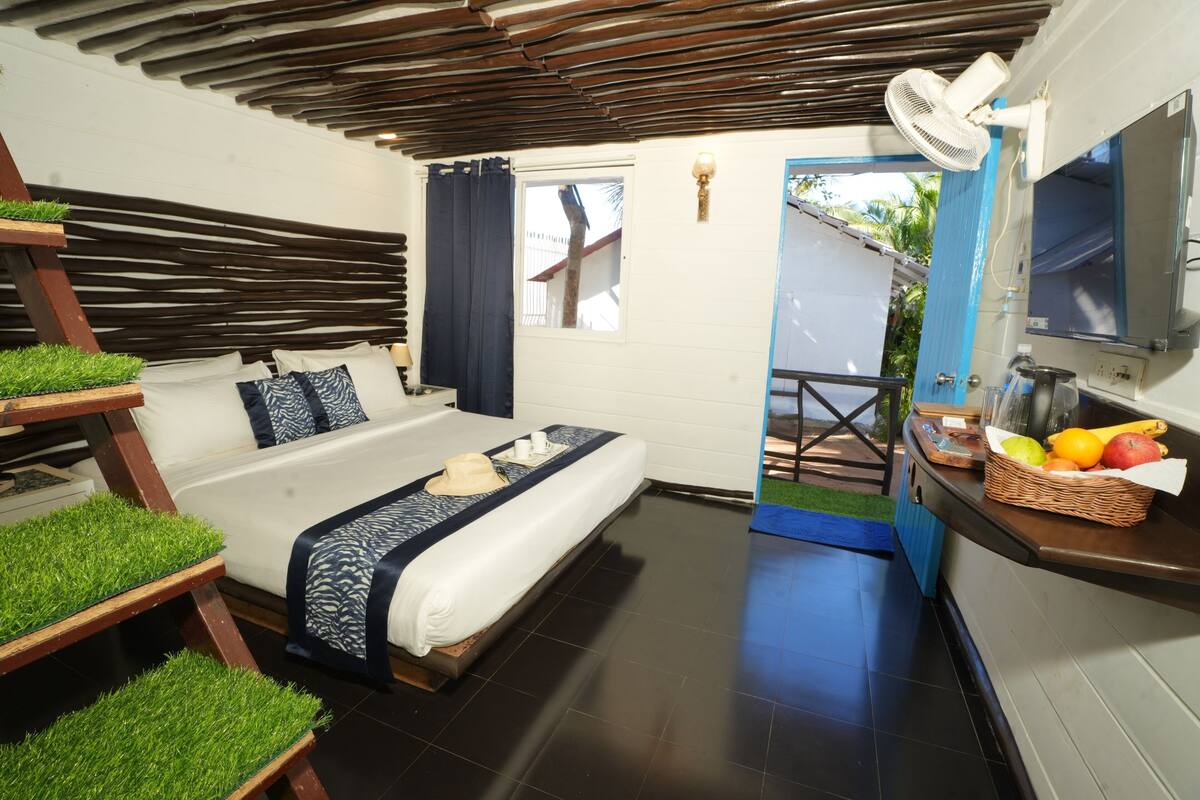 A modern bedroom with a bed, a wooden ceiling, a small balcony, and a breakfast bar with fruit.