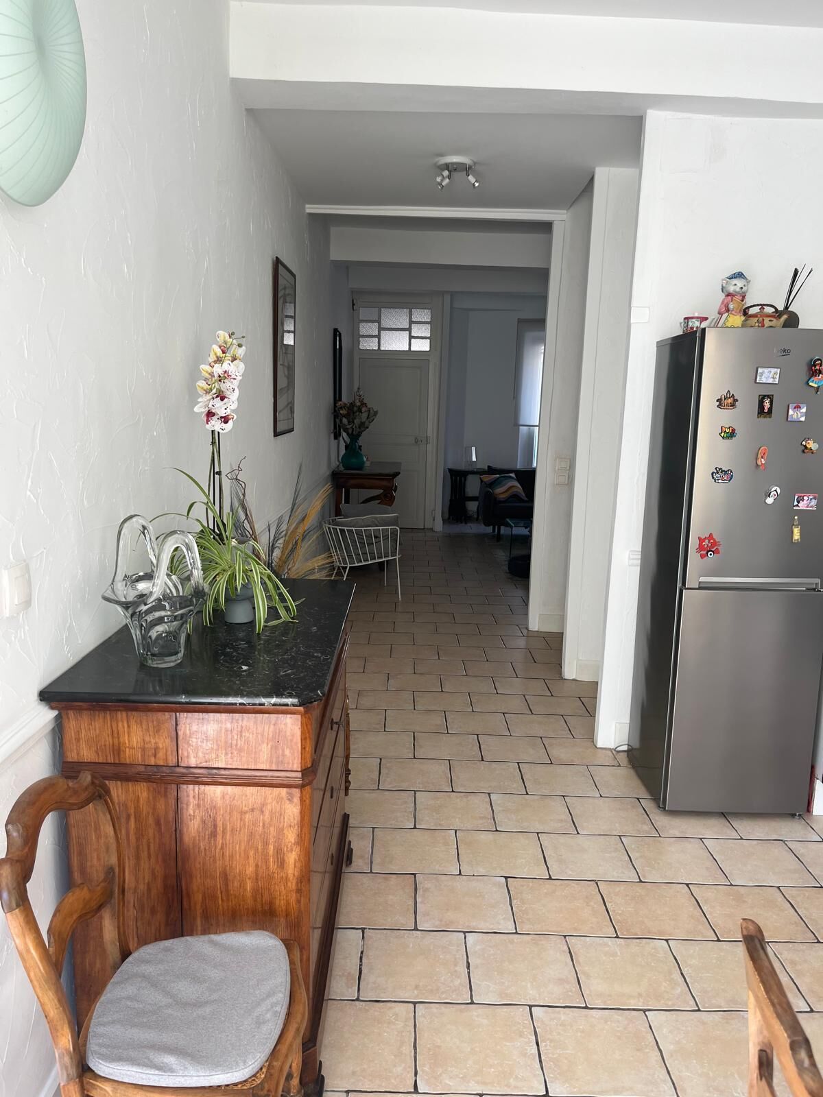 Una cocina con una mesa de madera, sillas y un refrigerador.