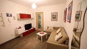 Ein Wohnzimmer mit Fernseher, einer Couch, einem Couchtisch und einem Schrank.