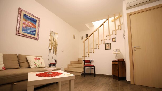 Ein Wohnzimmer mit einer Couch, einem Couchtisch, einer Treppe und einer Tür.