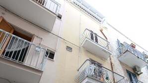 Ein mehrgeschossiges Gebäude mit Balkonen, Holztüren und Blick auf die Straße.