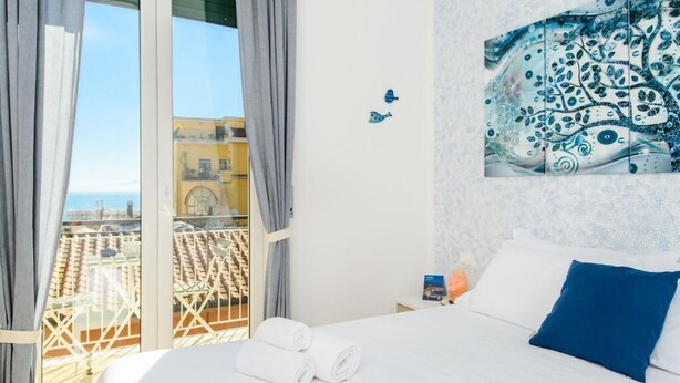 Une chambre d’hôtel avec un lit, une vue sur la ville depuis un balcon et un élément décoratif mural.