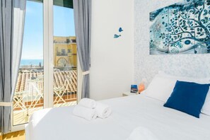 Ein Hotelzimmer mit Bett, Blick auf die Stadt vom Balkon und einer Wanddekoration.