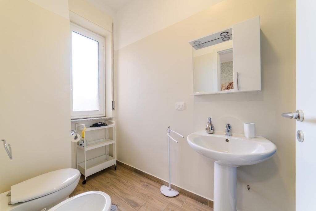 A small, clean bathroom with a toilet, sink, and window.