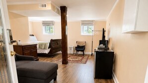 A spacious room with hardwood flooring, a large bed, a desk, and a chair.