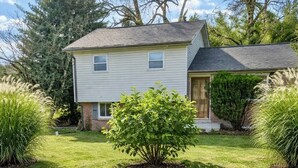 A two-story house with a well-maintained lawn and a small bush in the front yard.