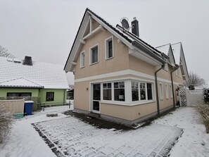 A two-story house with a sloped roof, a large bay window, and a visible chimney. - Vacation home Strandburg - family-friendly, close to the beach, sauna (Zingst)