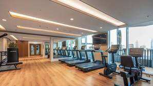 A gym with treadmills, exercise bikes, and a wooden floor. - Stayshort - Elegant 1 Bedroom in Emaar Beachfront That Sleeps 2 (Dubai)