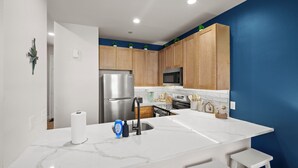 A modern kitchen with wooden cabinets, stainless steel appliances, and a marble countertop. - Cozy Beach Apartment in Soulard (St. Louis)
