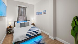 A bedroom with a bed, nightstands, a ceiling fan, artwork on the wall, and a plant. - Cozy Beach Apartment in Soulard (St. Louis)