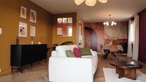 Una sala de estar moderna con un sofá blanco, una consola negra y un comedor con mesa y sillas.