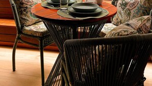 A dining area with wicker chairs, a round table, and a small potted plant. - Flat Jacuzzi Ocean Art Park by Living (João Pessoa)