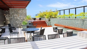 An outdoor patio with a stone wall, seating area, and a view of the ocean. - Flat Jacuzzi Ocean Art Park by Living (João Pessoa)