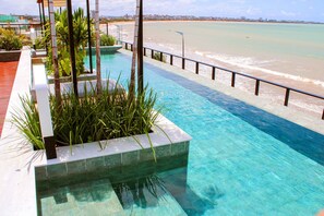 A clear blue pool with a view of the beach and ocean. - Flat Jacuzzi Ocean Art Park by Living (João Pessoa)