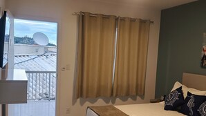 Une chambre d’hôtel avec un lit, une table de chevet, une fenêtre avec des rideaux et une vue sur un bâtiment à l’extérieur.