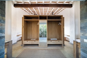 A spa room with wooden benches, a mirrored wall, and a ceiling fan. - Inkaterra Cabo Blanco (El Alto)