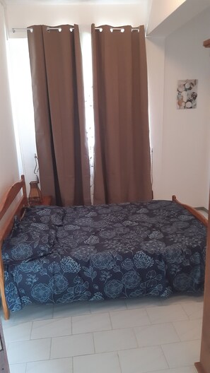 A room with a bed, curtains, a small table, and a wall art piece. - Bliss, a breathtaking and budget friendly apartment in Blue Bay  (Blue Bay)