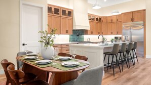 Una cucina moderna con mobili in legno, un frigorifero in acciaio inossidabile e una zona pranzo con tavolo e sedie in legno.