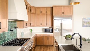 Una cucina moderna con mobili in legno, un frigorifero in acciaio inossidabile, un forno a microonde e un piano cottura a gas.