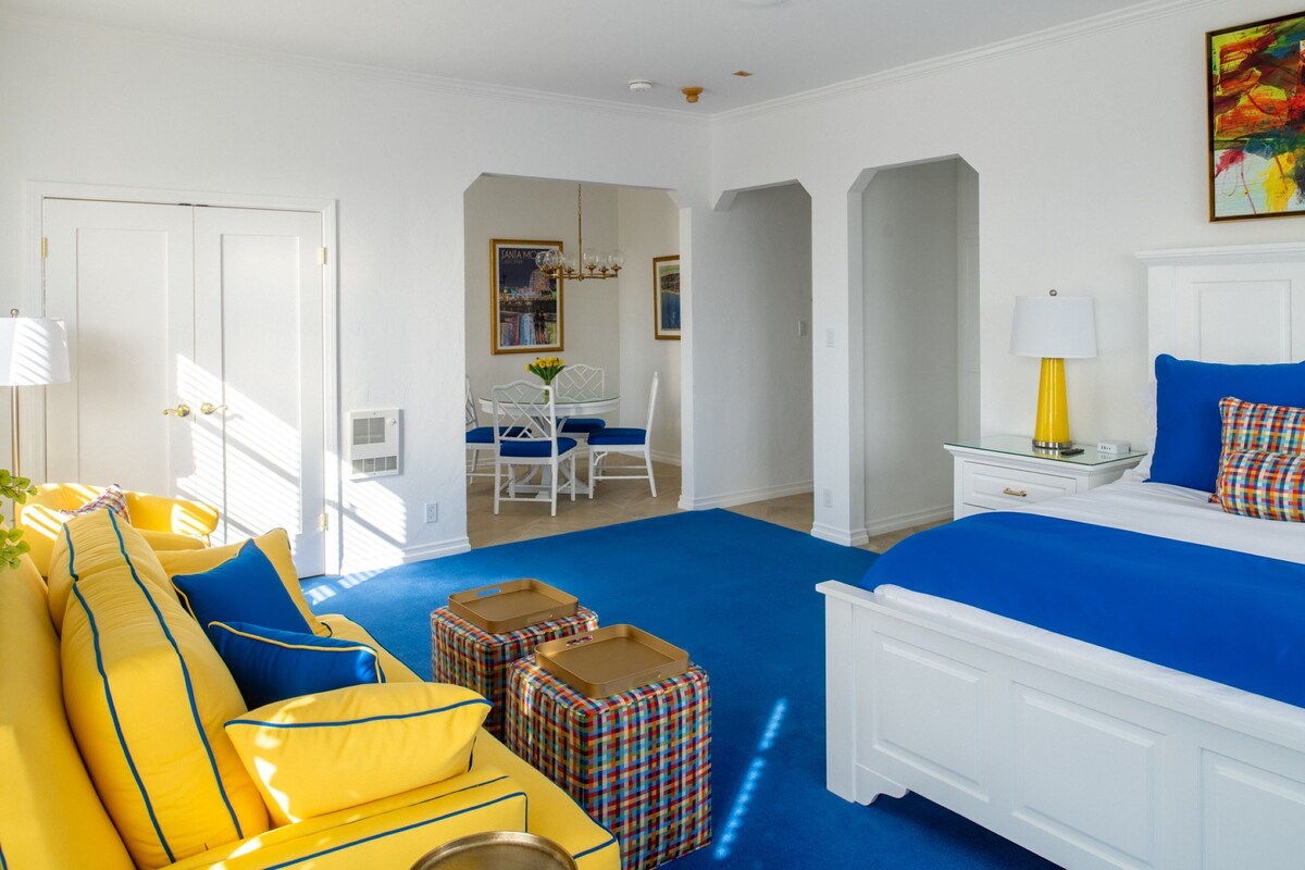 A bedroom with a bed, a sofa, a dining table, and chairs.