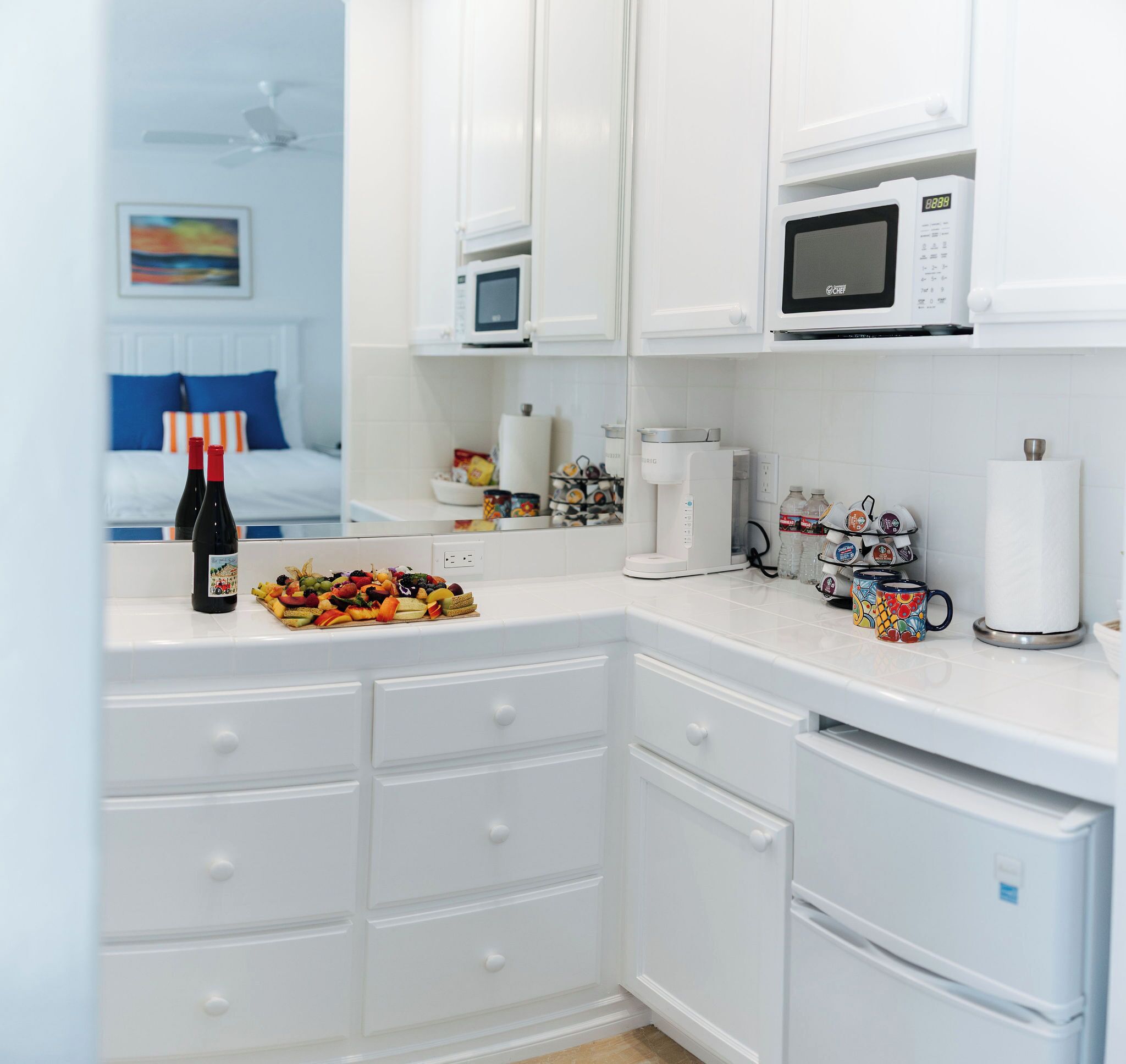 Une cuisine moderne avec des meubles blancs, une machine à café et un four à micro-ondes.