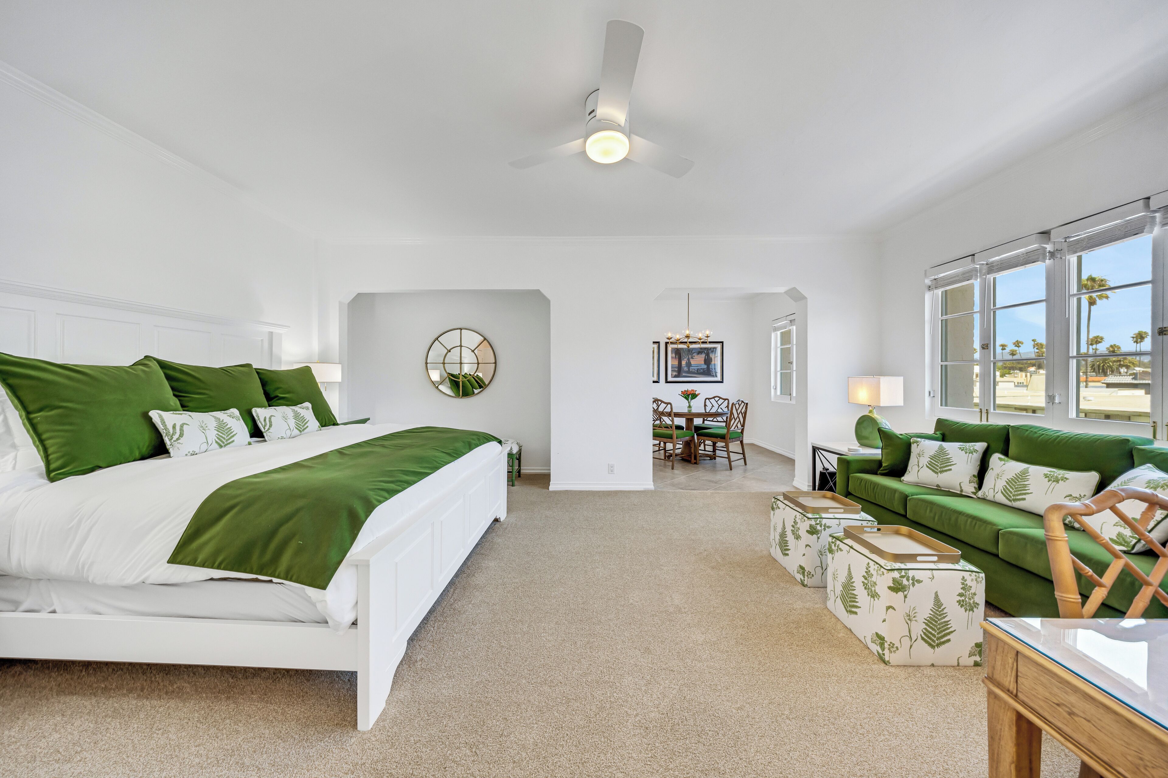 A bedroom with a bed, a green sofa, a dining table, and a chair.